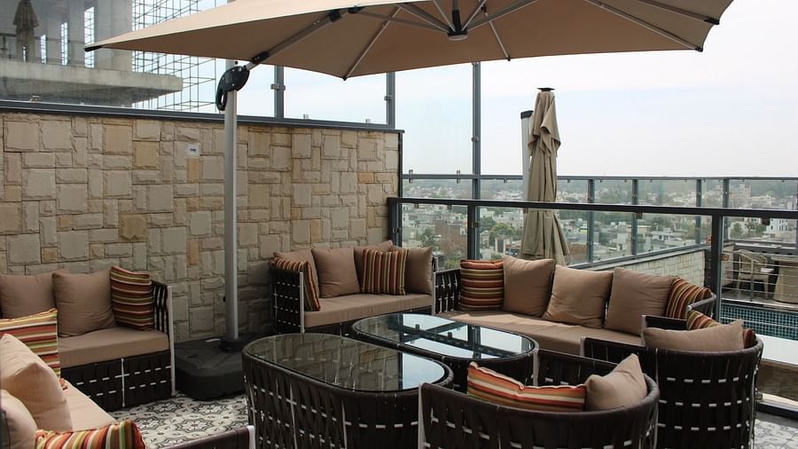 Rooftop lounge featuring sofas, pillows, and a patio offering stunning city views at BluSalzz Residence, Amritsar